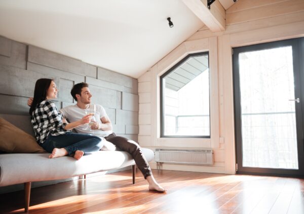 A young couple sitting on a sofa toasting the purchase of their new home