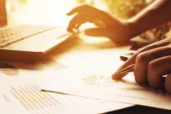 Businessman holding pen on charts and graph to find out the result at home office