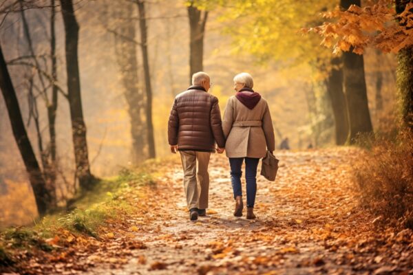 Retired couple holding hands walking in the autumn forest